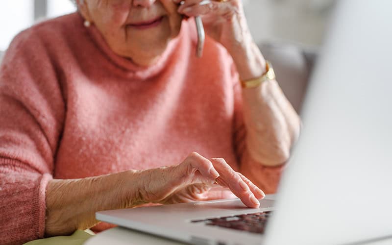 Older woman using laptop for cybersecurity awareness.