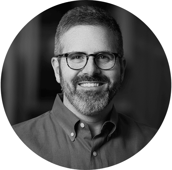 Cybersecurity expert smiling with glasses in professional portrait.