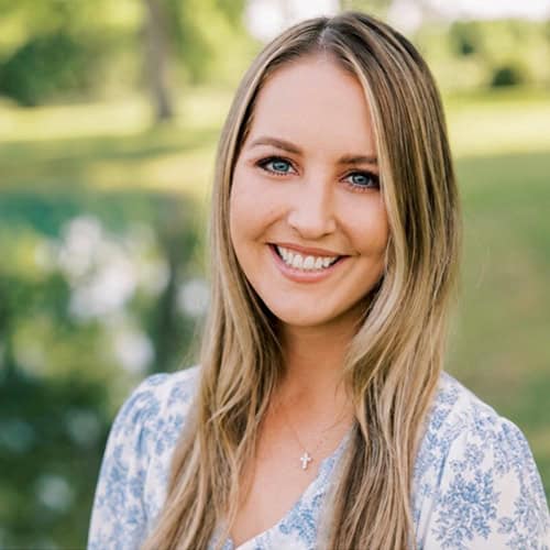 Smiling woman with blonde hair outdoors, sunny day, natural background.
