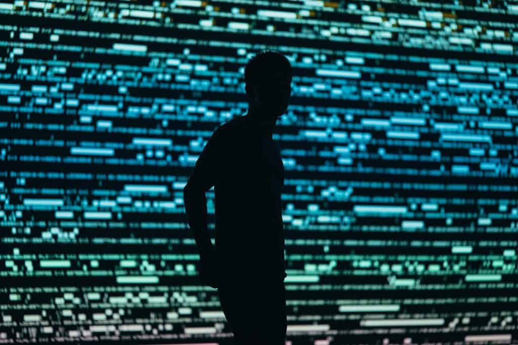 Silhouette of person in front of digital code background.