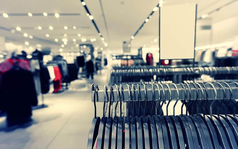 Retail store rack of empty hangers with blurred background.
